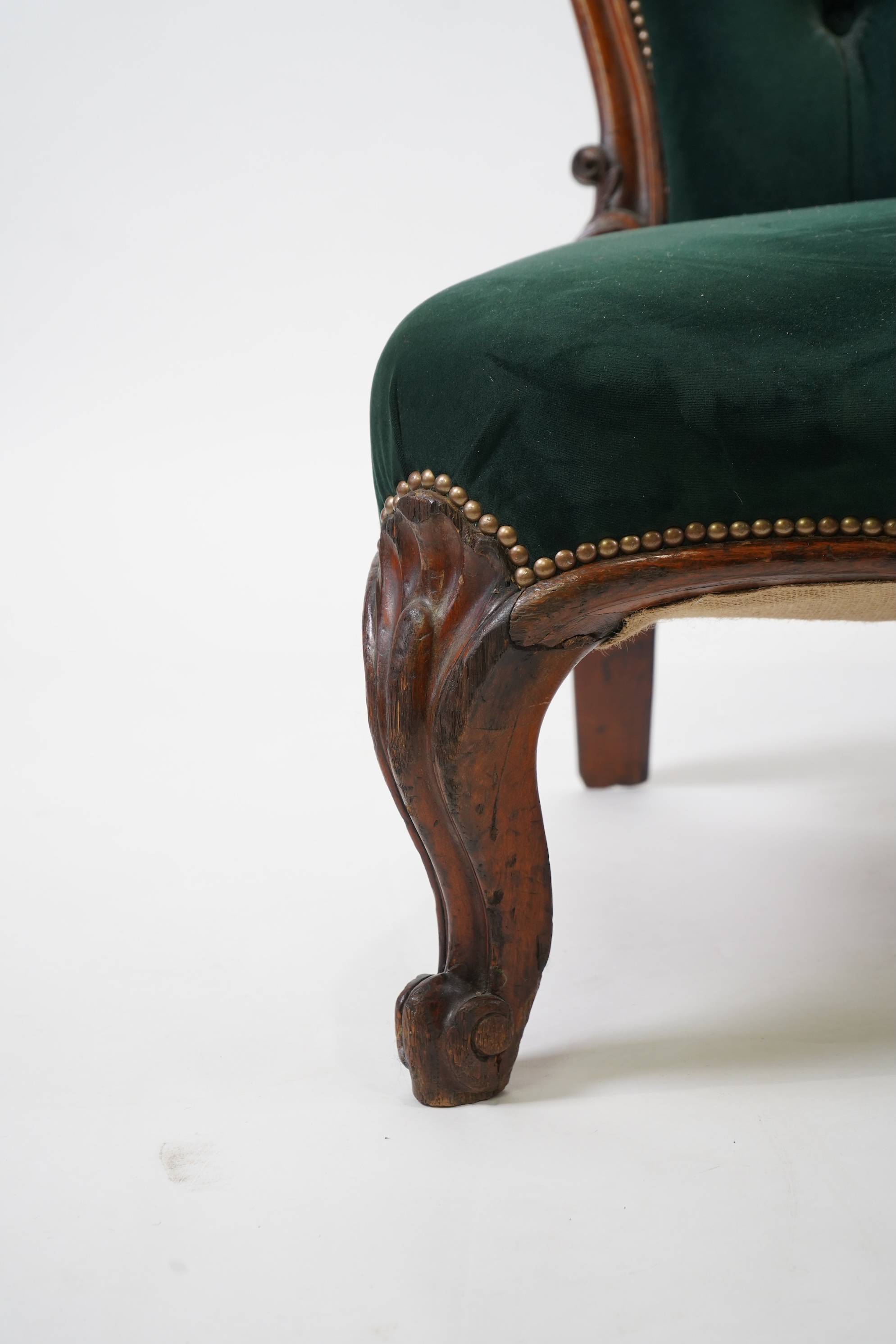 A pair of Victorian carved oak settees, recently re-upholstered in deep buttoned green velvet, the scroll carved crest rails over serpentine seats on cabriole front legs, 160cm wide, 96cm high, Provenance - previously gi